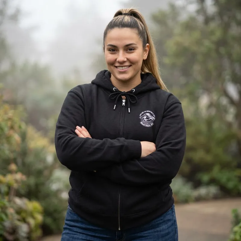Woman wearing a black zip hoodie with a small Mount Rainier badge design